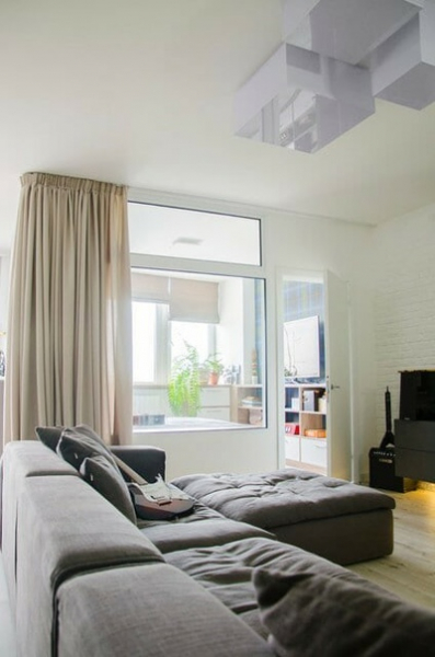 Стеклянная перегородка между гостиной и спальней позволяет получить достаточно естественного света по всей квартире.